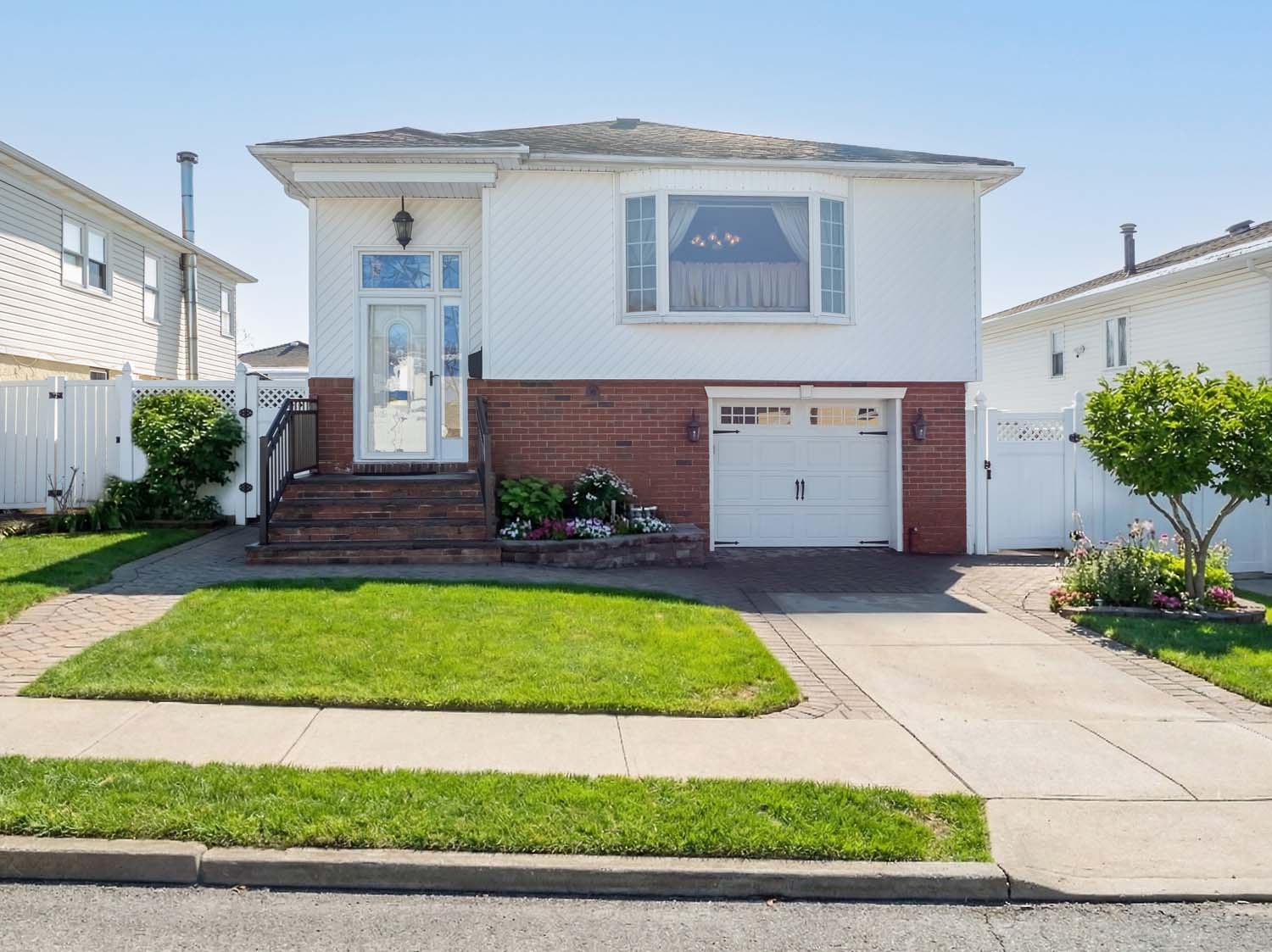 Front view of a renovated all-brick Cape Cod style home at 553 Oakland Avenue in Sunset Hill, Staten Island. Features new pavers, driveway, and Trex deck.