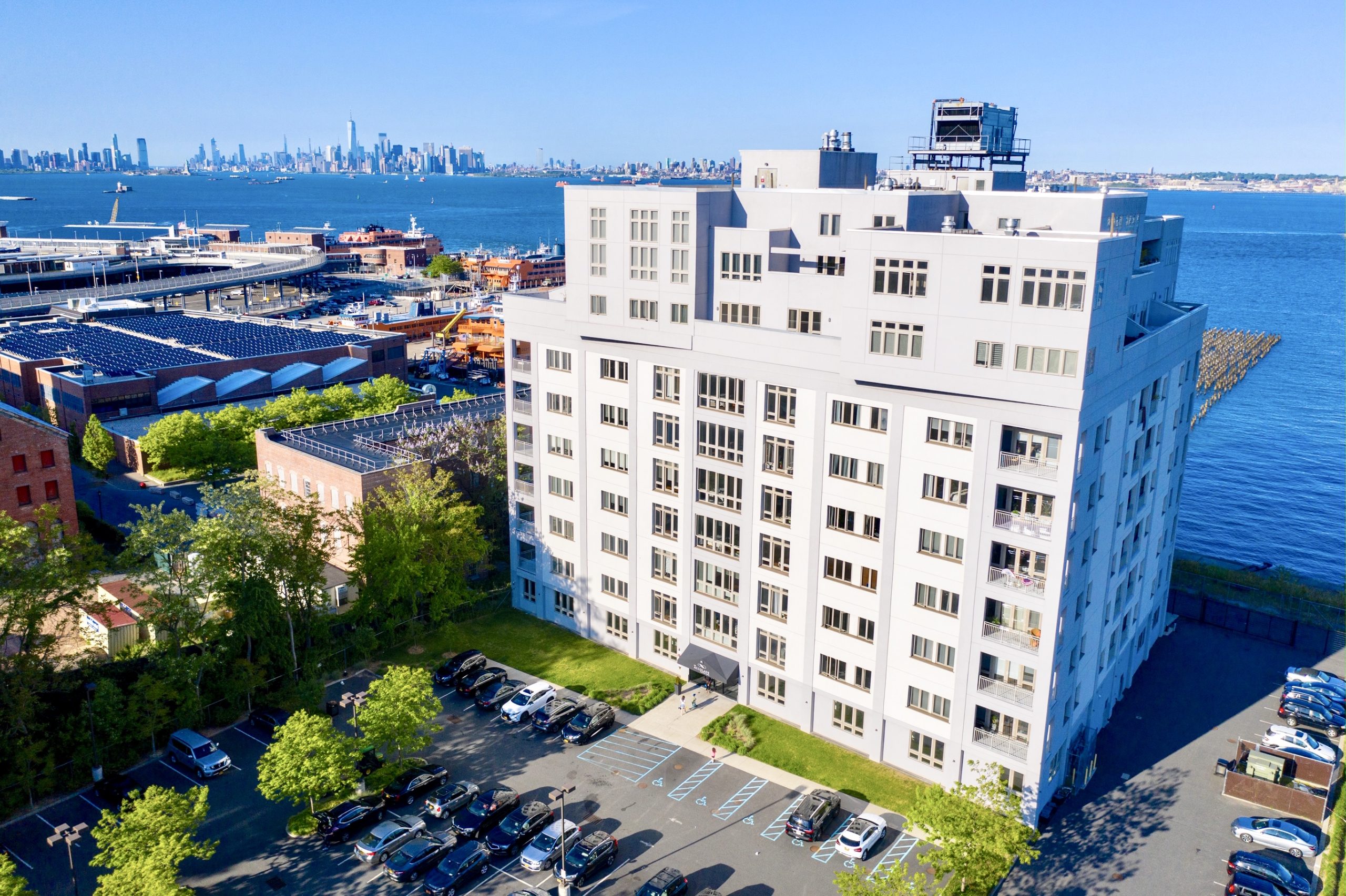 Aerial view of The Accolade Condominiums at 90 Bay St. Landing in St. George, Staten Island, overlooking New York Harbor and the Manhattan skyline.