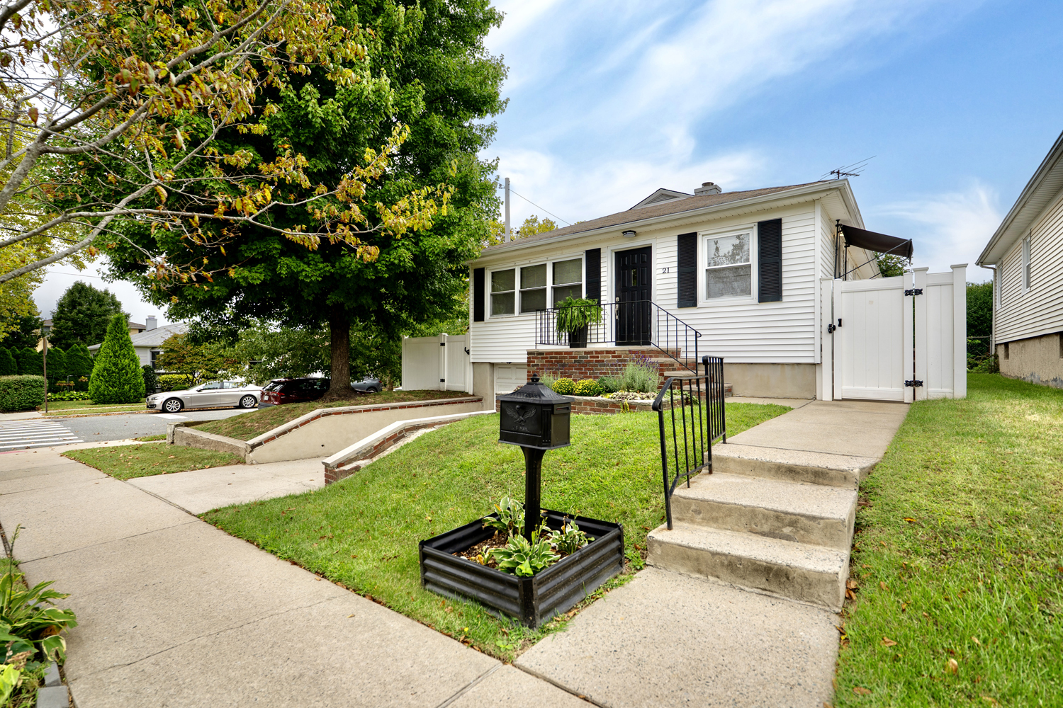 Front exterior of the raised ranch at 21 Bellhaven Place in Westerleigh, Staten Island, with white siding and black shutters.